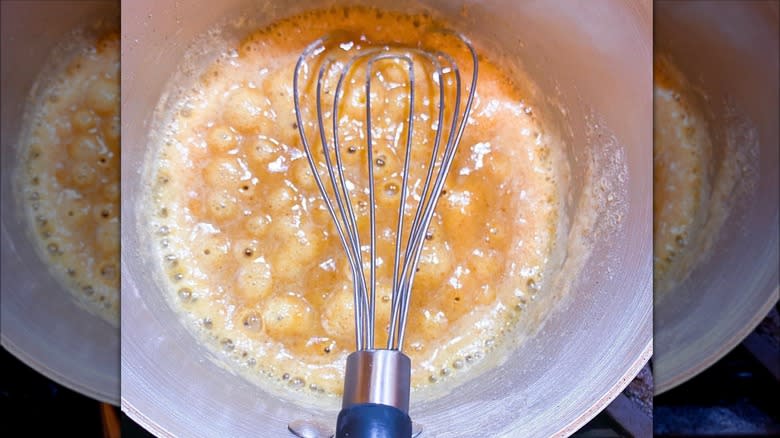 flat whisk in a pot of bubbling food 