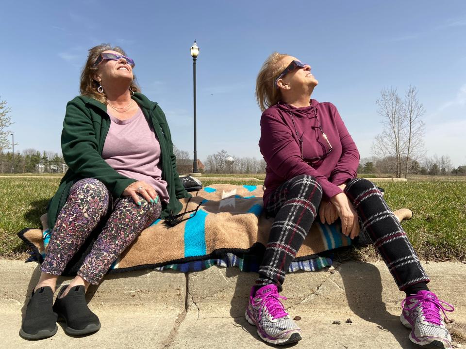 Sandra Schmidt, left, and Sharon Parr, both of Lansing, sit in a parking lot at the back of the Eastwood Towne Center in Lansing Township at about 3 p.m. Parr said they got the glasses at Meijer last week and planned on a secluded spot away from crowds.