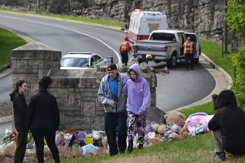 People walk away after leaving items at nn entry to Covenant School which has become a memorial for shooting victims, Tuesday, March 28, 2023, in Nashville, Tenn. (AP Photo/John Amis)