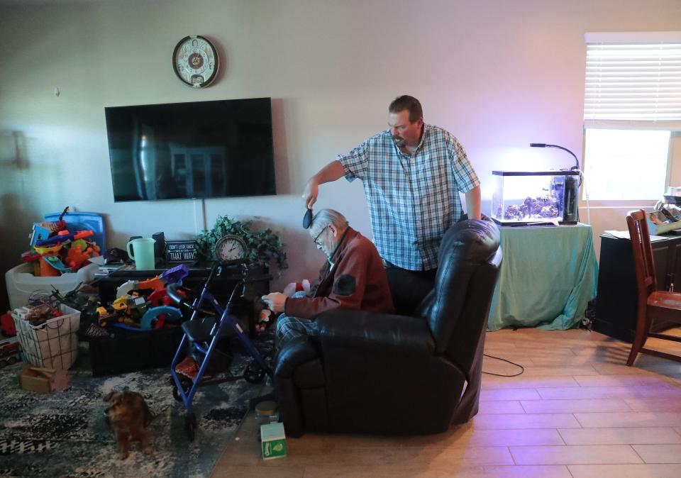 George Adair combs his father Francis' hair inside their Buckeye home Feb. 14, 2021. George takes care of his father who has dementia after his mother Phyllis, a flight attendant for American Airlines, died Feb. 2 from COVID-19.