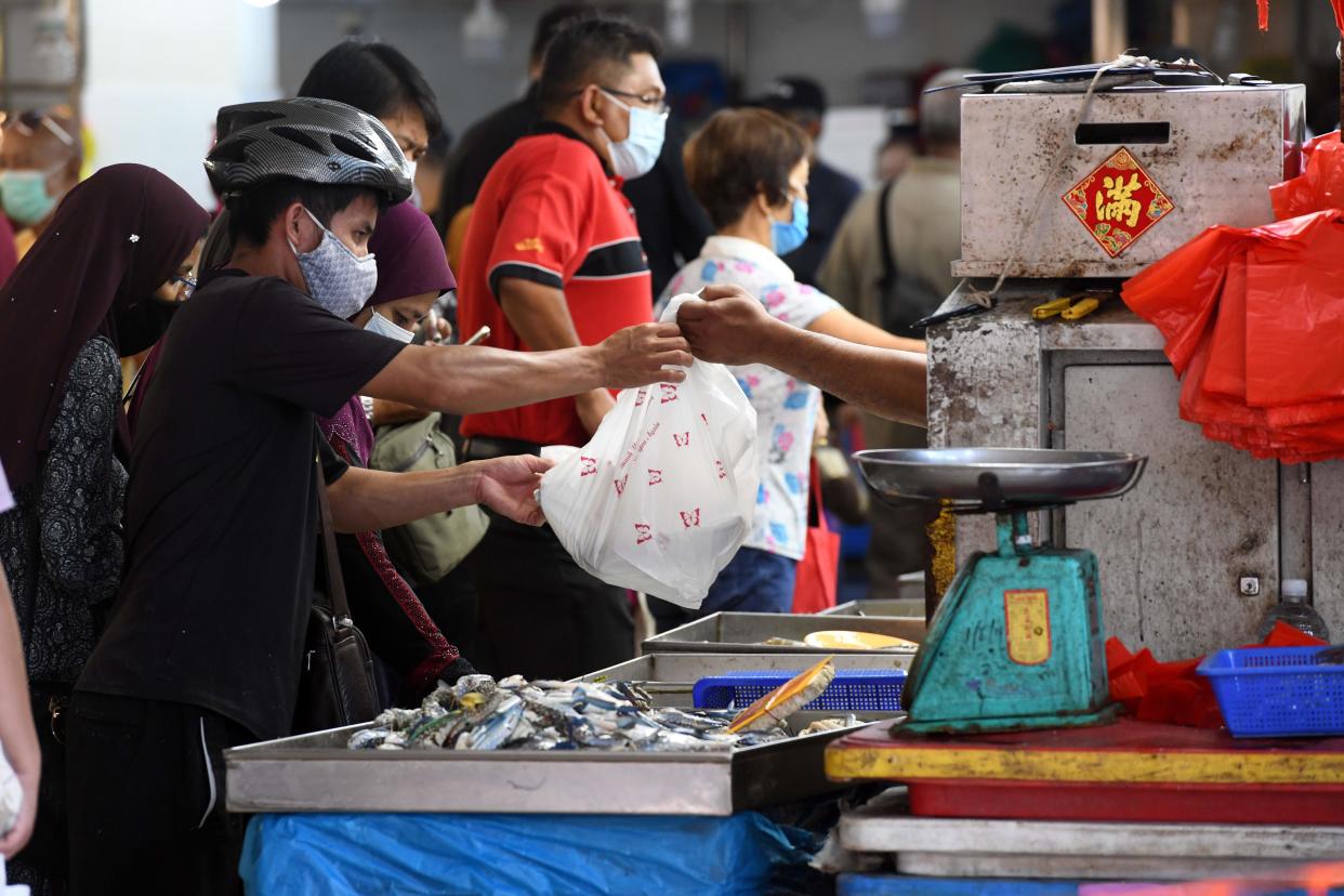 A man, wearing a face mask as a preventive measure against the spread of the COVID-19 novel coronavirus, makes a purchase at a fish stall in Geylang Serai wet market in Singapore on April 23, 2020, ahead of the start of the holy Muslim month of Ramadan. (Photo by Roslan RAHMAN / AFP) (Photo by ROSLAN RAHMAN/AFP via Getty Images)