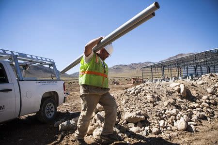 Electrician Darrell Scronce carries conduits at the construction site of a battery systems plant at the Tahoe-Reno Industrial Center in McCarran, Nevada, September 16, 2014. REUTERS/Max Whittaker