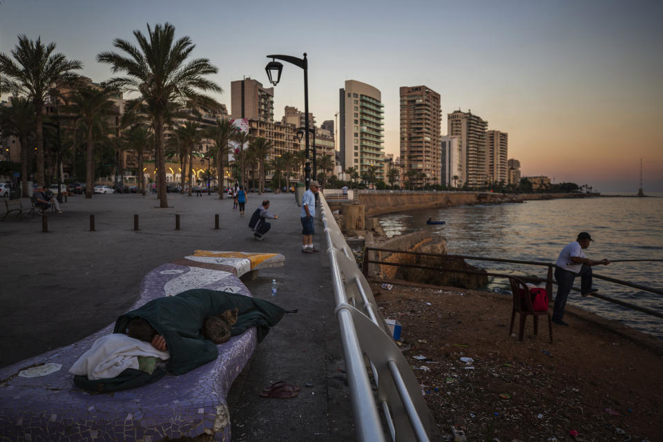 FILE - A homeless Lebanese woman and her cat sleep on a bench as the sun rises over the Mediterranean Sea in Beirut, Lebanon, on June 18, 2021. The World Bank has approved a $300 million additional financing to the poor in Lebanon in which families that live in poverty will get cash payments to help them through the country's historic economic meltdown, the World Bank said in a statement released Friday, May 26, 2023. (AP Photo/Hassan Ammar, File)