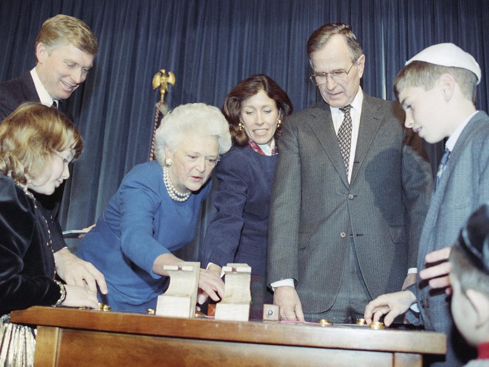 President George H. W. Bush and first lady Barbara Bush participate in a Hanukkah celebration by playing the children's holiday game of dreidel at the White House in 1990.