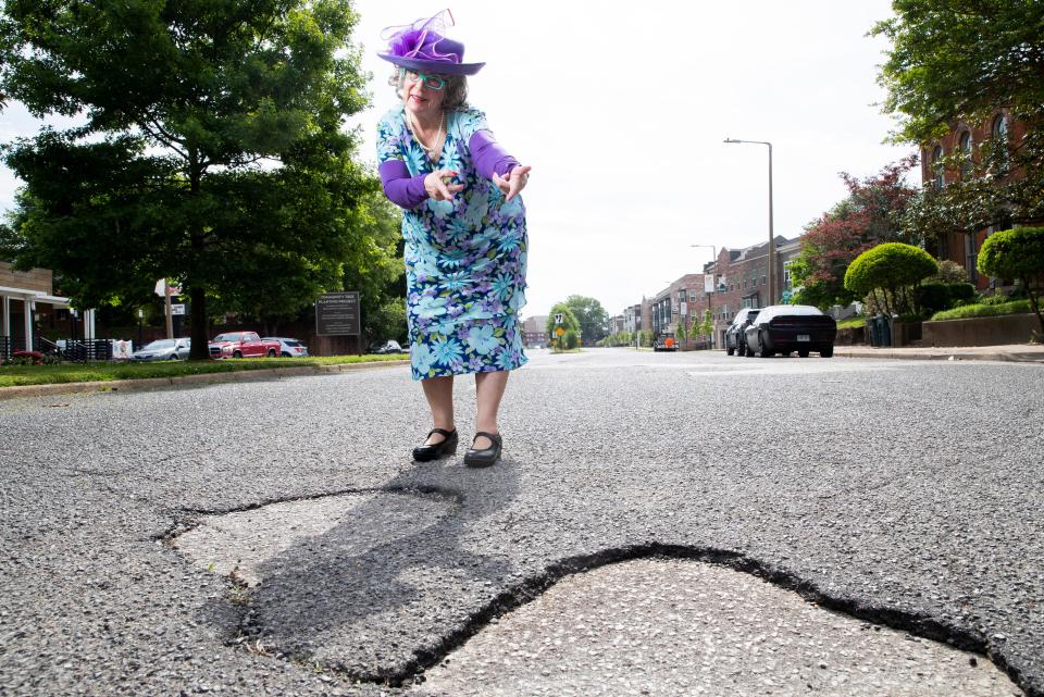 Sybil Presley, known as “The Pothole Lady,” poses for a portrait next to multiple potholes on Jefferson Avenue in Memphis, Tenn., on Friday, April 26, 2024. Presley appeared as this character at a recent Memphis City Council meeting and sang an original song, “The Pothole Blues.”