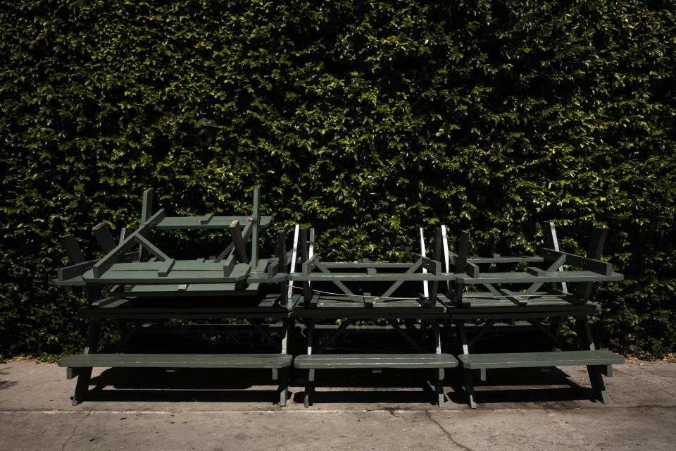 Mesas y bancos de picnic, apilados contra una pared en el exterior de un bar cerrado temporalmente por la pandemia del coronavirus, en Los Ángeles, el 8 de julio de 2020. (AP Foto/Jae C. Hong)