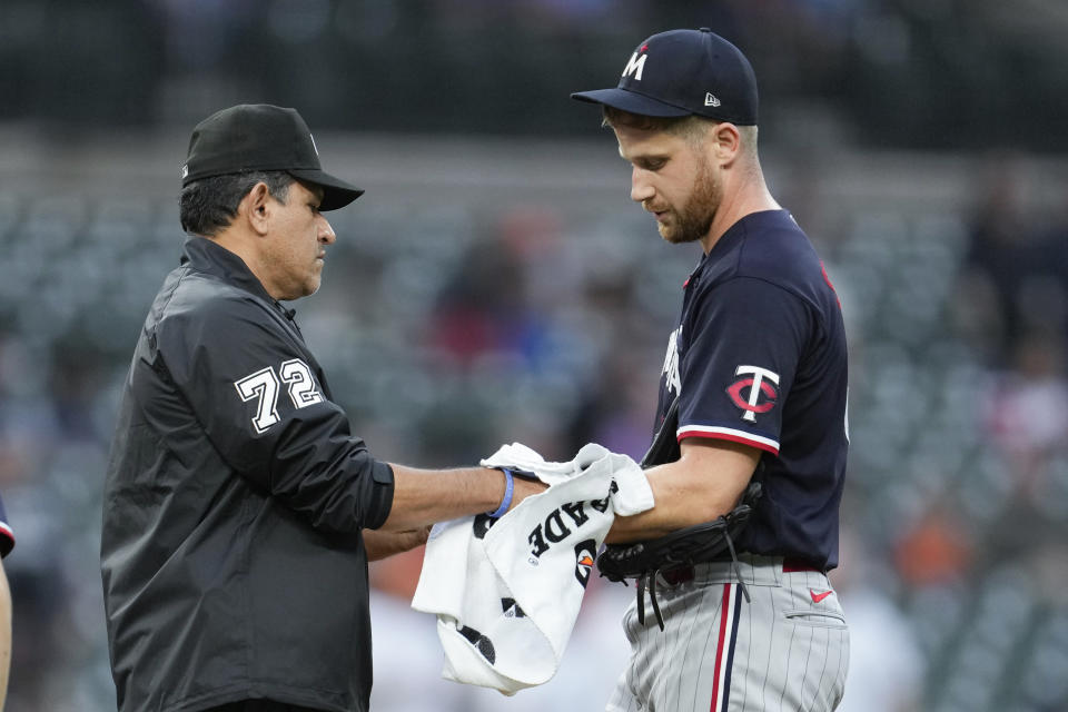 Umpire Alfonso Marquez wipes the arm of Minnesota Twins relief pitcher Brock Stewart with a towel in the sixth inning of a baseball game against the Detroit Tigers, Friday, June 23, 2023, in Detroit. (AP Photo/Paul Sancya)