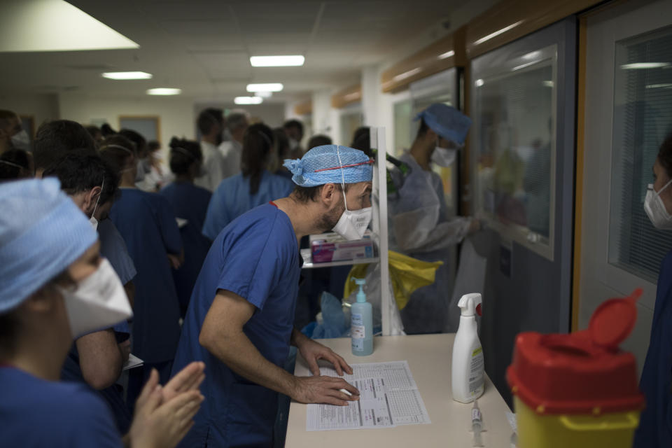 A medical worker peers through the glass of an ICU room containing a COVID-19 patient at the La Timone hospital in Marseille, southern France, Thursday, Nov. 12, 2020. (AP Photo/Daniel Cole)