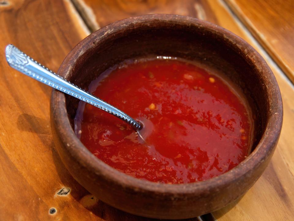 Bowl of a red sauce with a spoon on it on wooden table