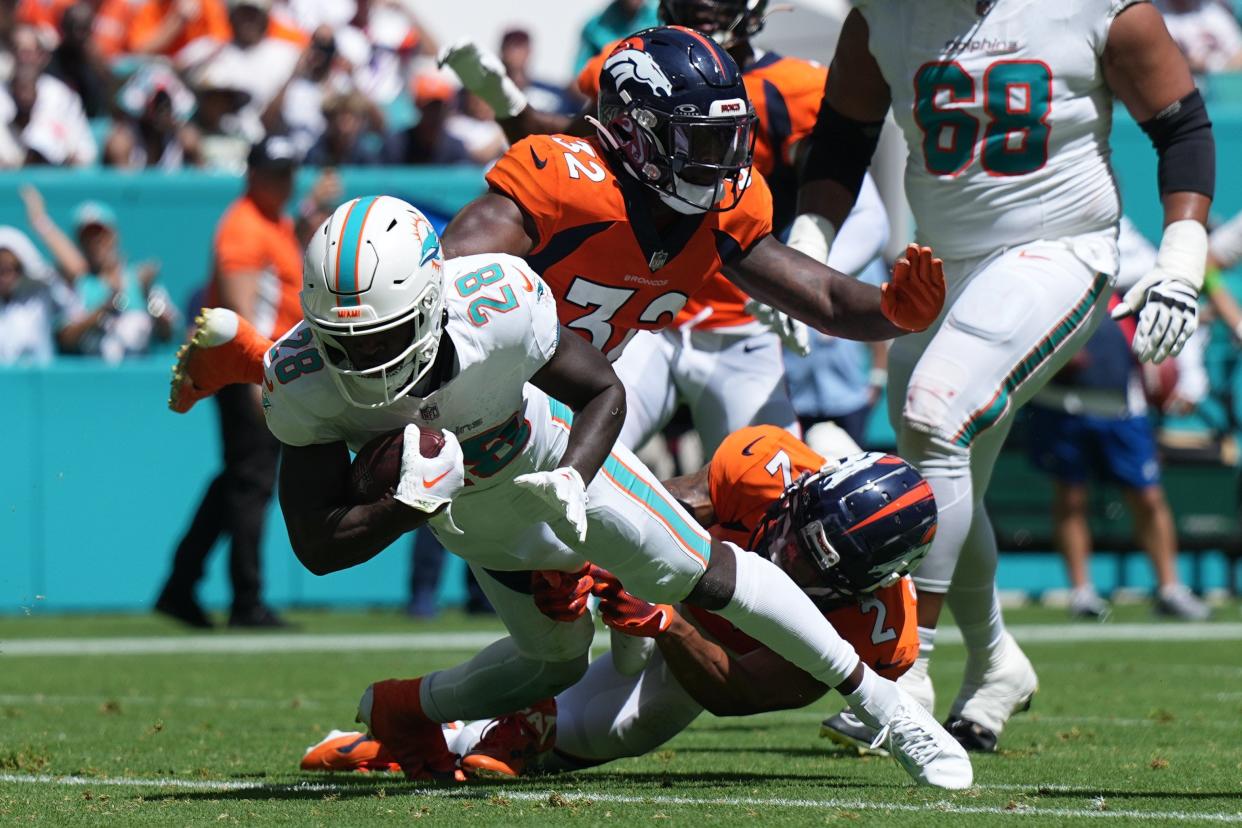 Miami Dolphins running back De'Von Achane (28) scores a touchdown in the second quarter as Denver Broncos cornerback Pat Surtain II (2) and safety Delarrin Turner-Yell (32) try to make the tackle on the play during the first half of an NFL game at Hard Rock Stadium in Miami Gardens, Sept. 24, 2023.