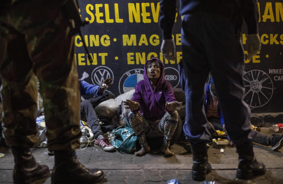 A homeless woman talks to South African Defense Forces and police officers as they patrol the street in Johannesburg, South Africa, May 1, 2020, as the curfew begins. (AP Photo/Themba Hadebe)
