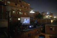 The film Aladdin is projected on a screen set up on the roof of a home in the Petare neighborhood of Caracas, Venezuela, late Monday, June 1, 2020. A neighborhood group called The Download Zone set up the movie as a free entertainment option for families cooped up since mid-March under the COVID-19 quarantine. (AP Photo/Ariana Cubillos)