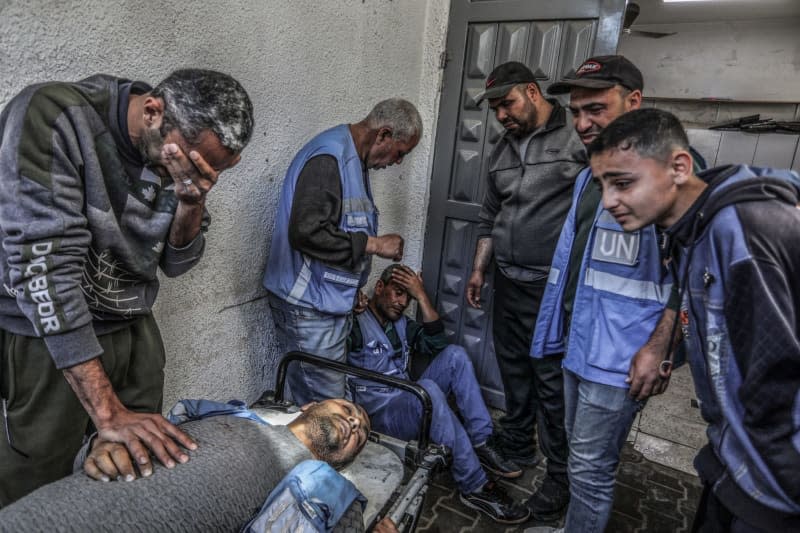 Palestinians mourn around the body of a UN staff who was killed in an Israeli air strike near a warehouse of the United Nations Relief and Works Agency for Palestine Refugees (UNRWA), at Al-Najjar Hospital in Rafah, southern Gaza Strip. Abed Rahim Khatib/dpa