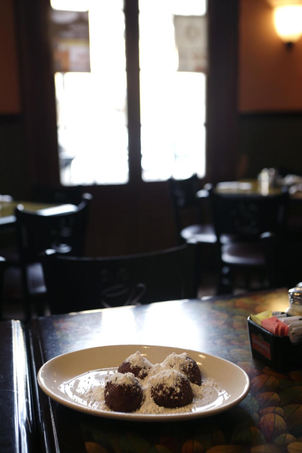 In this Monday, Jan. 28, 2013 photo, calas cake with powdered sugar is seen at The Old Coffeepot Restaurant in the French Quarter of New Orleans. Tired of celebrating Mardi Gras with the same old beignets? Make the switch to calas, tangy rice fritters born to go with cafe au lait. Calas (KAH-luhs) can be tough to find these days, but they have a rich history that spans the great cuisines of New Orleans. (AP Photo/Gerald Herbert)