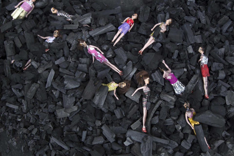 FILE - In this March 9, 2017 file photo, charred-stained dolls placed on a bed of charcoal are part of an artists' installation placed at the front gate of the presidential house in remembrance of the victims of a fire at the Virgen de la Asunción Safe Home, in Guatemala City. The girls' hell at the government-run home began long before the deadly fire, as documented in several warnings from four different agencies. At least two orders for closure were ignored. (AP Photo/Luis Soto, File)