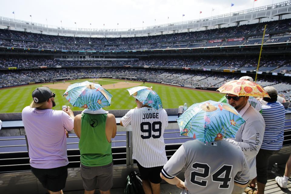 Fans use umbrella hats to protect themselves from the sun during the sixth inning of a baseball game between the New York Yankees and the Colorado Rockies Saturday, July 20, 2019, in New York. (AP Photo/Frank Franklin II)