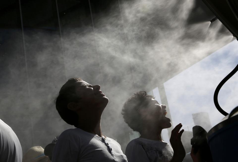 Children cool themselves under misting fans at the Australian Open tennis tournament at Melbourne Park, Australia, January 21, 2016. REUTERS/Tyrone Siu