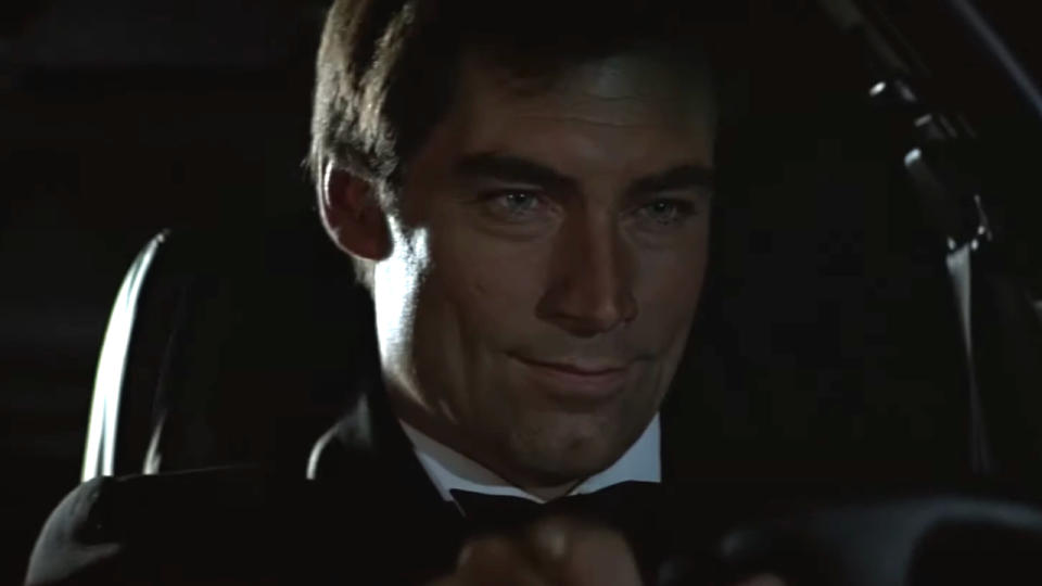 Timothy Dalton sitting behind the wheel with a smile in The Living Daylights.