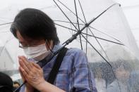 A woman prays for the victims of the arson attack in front of the torced Kyoto Animation building n Kyoto