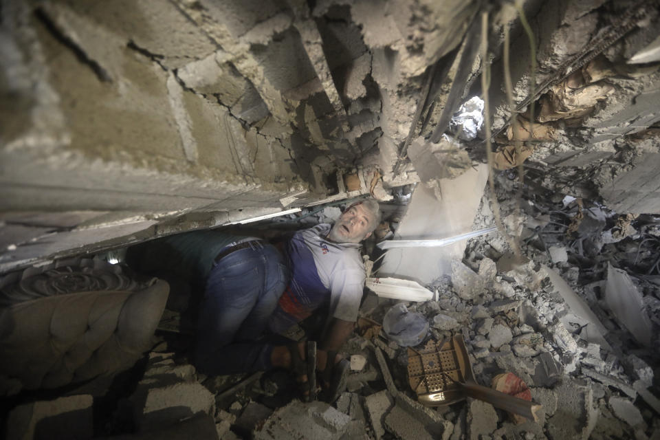 Palestinians try to release a man from under the rubble of a destroyed building following an Israeli airstrike in Khan Younis refugee camp, southern Gaza Strip, Tuesday, Nov. 7, 2023. (AP Photo/Mohammed Dahman)