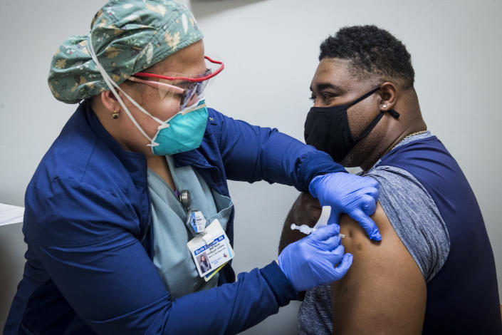 FILE - In this Feb. 11, 2021, file photo, registered nurse Marife Edquilang, left, administers a dose of Pfizer COVID-19 vaccine to Anthony Monroe during a vaccination drive at Texas Southern University in Houston. At least 11 states opened vaccine eligibility to all adults this week in a major expansion of COVID-19 shots for tens of millions of Americans amid a worrisome increase in virus cases and concerns about supply and demand for the vaccines. States opening eligibility to anyone ages 16 and older on Monday included Texas, Oklahoma, Louisiana, Ohio and Kansas. (Brett Coomer/Houston Chronicle via AP)