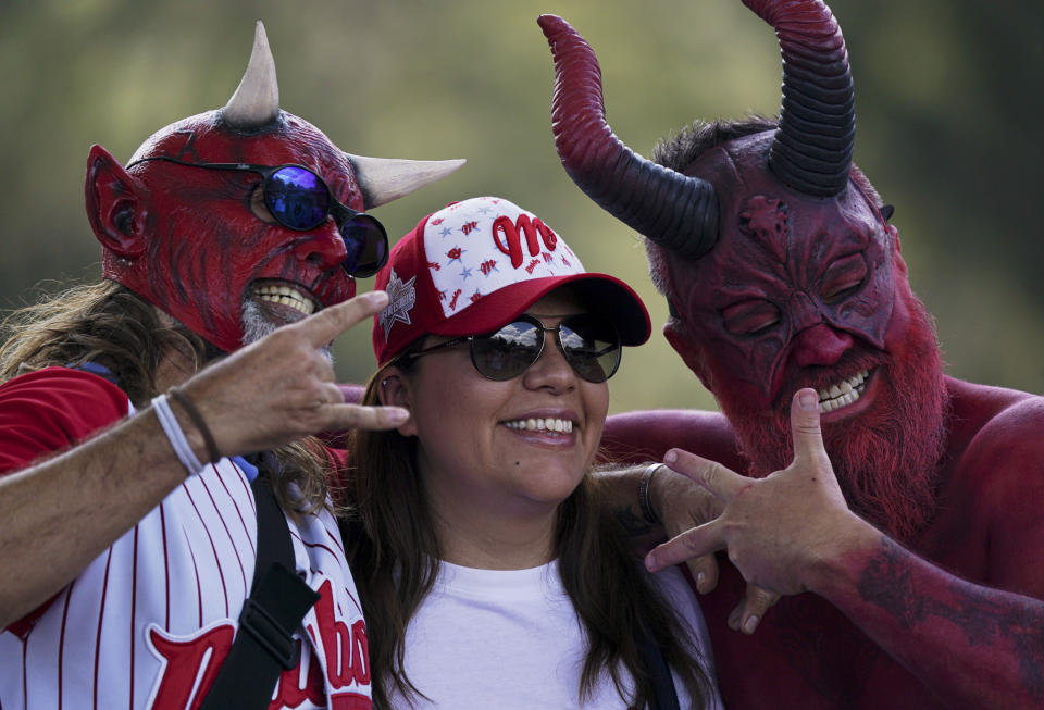 Fanáticos de los Diablos Rojos de México posan para fotos durante el juego contra los Tigres de Quintana Roo por la liga mexicana de béisbol en el estadio Alfredo Harp Helú, el domingo 23 de abril de 2023, en la Ciudad de México. (AP Foto/Fernando Llano)