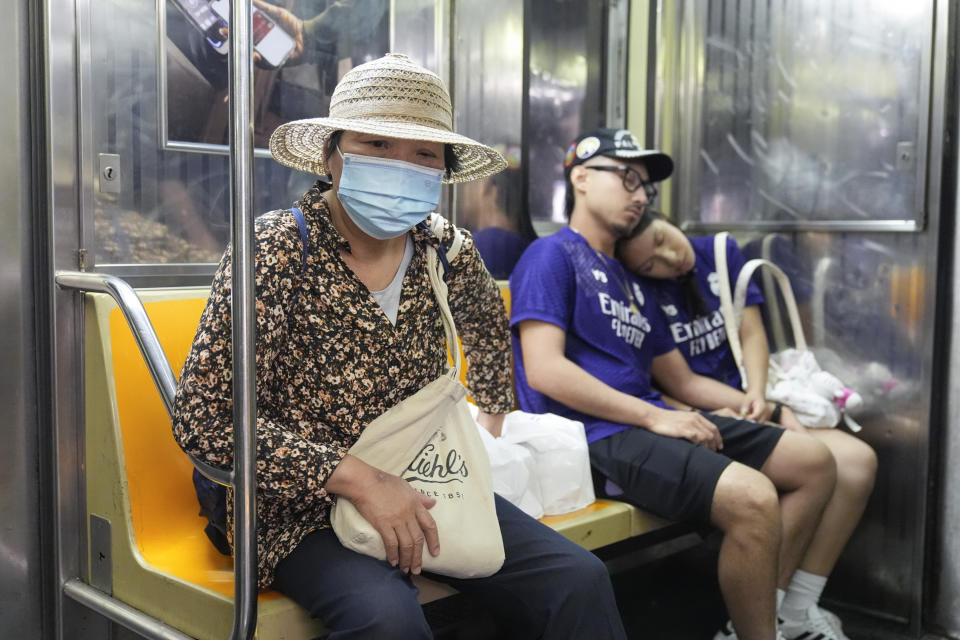 Commuters, one wearing a mask, ride the subway in New York, Friday, June 14, 2024. New York Gov. Kathy Hochul says she is considering a ban on face masks in the New York City subway system, following what she described as concerns over people shielding their identities while committing antisemitic acts. (AP Photo/Seth Wenig)