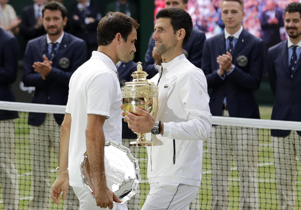 FILE - In this July 14, 2019, file photo, second placed Switzerland's Roger Federer, left, walks past winner Novak Djokovic, of Serbia, during trophy ceremonies after the men's singles final match at the Wimbledon Tennis Championships in London. (AP Photo/Ben Curtis, File)