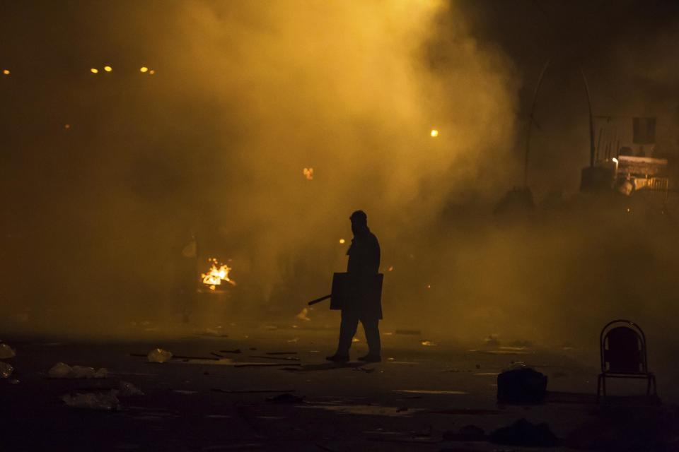 A supporter of Tahir ul-Qadri, Sufi cleric and leader of political party Pakistan Awami Tehreek (PAT), holds a police shield he stands amidst tear gas smoke during clashes with riot police as Tahir ul-Qadri supporters went towards the Prime Minister's house during Revolution March in Islamabad August 30, 2014.(REUTERS/Zohra Bensemra)