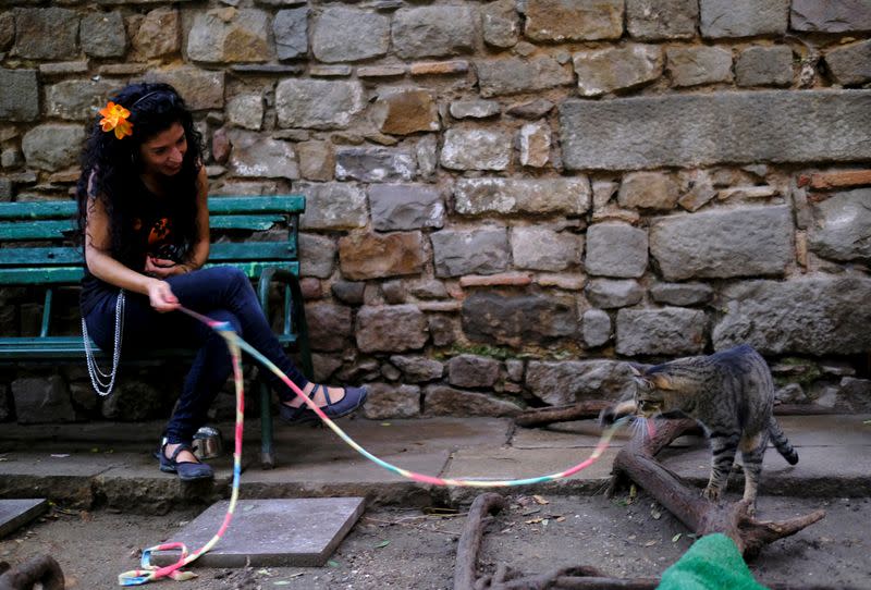 Álex Salvador, dueña del refugio para gatos callejeros El Jardinet dels Gats, juega con un gato en Barcelona