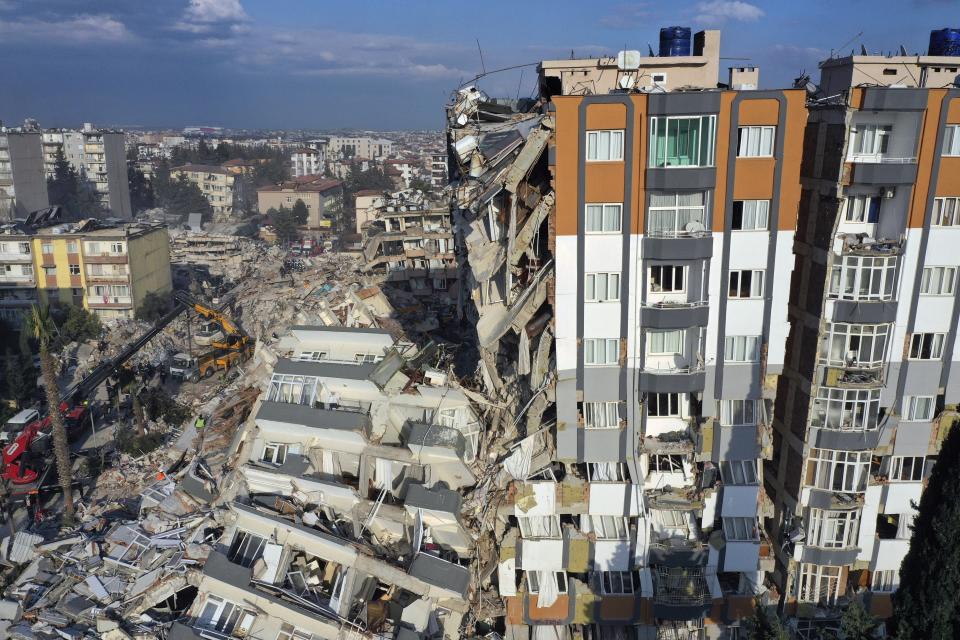 Cranes remove debris next to destroyed buildings in Antakya, southeastern Turkey, Friday, Feb. 10, 2023. Rescuers pulled several earthquake survivors from the shattered remnants of buildings Friday, including some who lasted more than 100 hours trapped under crushed concrete after the disaster slammed Turkey and Syria. (AP Photo/Hussein Malla)