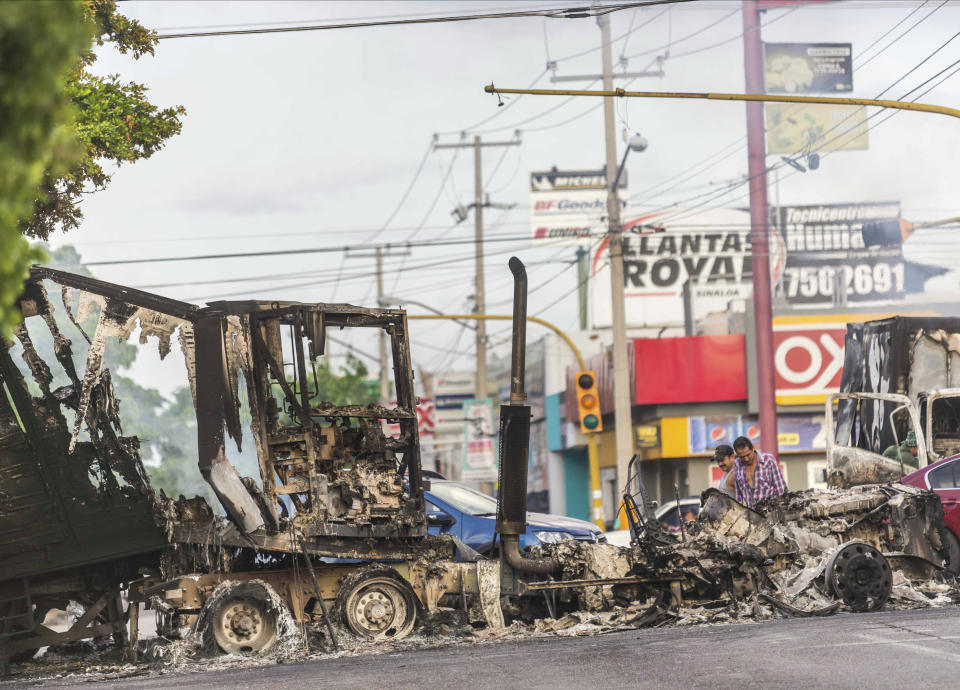 A burnt out semi truck used by gunmen smolders on an intersection, a day after street battles between gunmen and security forces in Culiacan, Mexico, Friday Oct. 18, 2019. Mexican security forces backed off an attempt to capture a son of imprisoned drug lord Joaquin "El Chapo" Guzman after finding themselves outgunned in a ferocious shootout with cartel enforcers that left at least eight people dead and more than 20 wounded, authorities said. (AP Photo/Augusto Zurita)