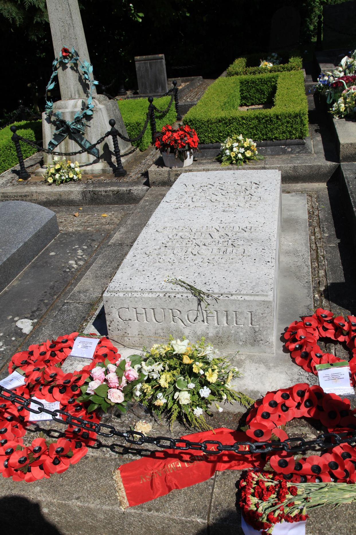 Winston Churchill's tomb in the family plot in the St. Martin Churchyard, Westminster Abbey, London surrounded by other elaborate tombs with flowers and paper poppies