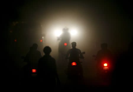 Motorcyclists ride through a haze on a road in the industrial town of Vapi, about 180 km (112 miles) north of Mumbai, in this November 23, 2009 file photo. REUTERS/Arko Datta/Files