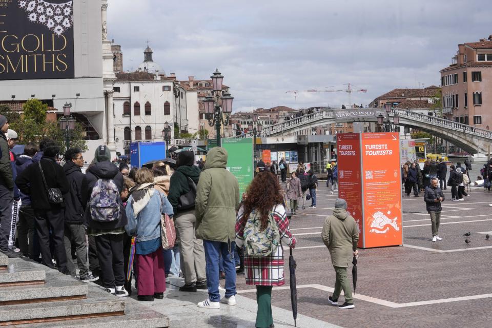 Tourists arrive outside the main train station in Venice, Italy, Wednesday, April 24, 2024. The lagoon city of Venice begins a pilot program Thursday, April 25, 2024 to charge daytrippers a 5 euro entry fee that authorities hope will discourage tourists from arriving on peak days. Officials expect some 10,000 people will pay the fee to access the city on the first day, downloading a QR code to prove their payment. (AP Photo/Luca Bruno)