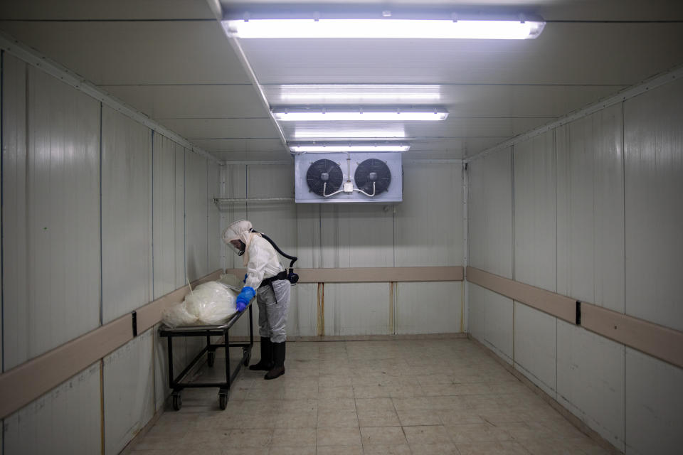 A worker from "Hevra Kadisha," Israel's official Jewish burial society, prepares a body before a funeral procession at a special morgue for COVID-19 victims in the central Israeli city of Holon, near Tel Aviv, Wednesday, Sept. 23, 2020. (AP Photo/Oded Balilty)