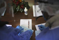 Municipal workers seal an envelope with a presidential election ballot from a resident at an elderly care home in Montijo, south of Lisbon, Tuesday, Jan. 19, 2021. For 48 hours from Tuesday, local council crews are collecting the votes from people in home quarantine and from residents of elderly care homes ahead of Sunday's presidential election. (AP Photo/Armando Franca)