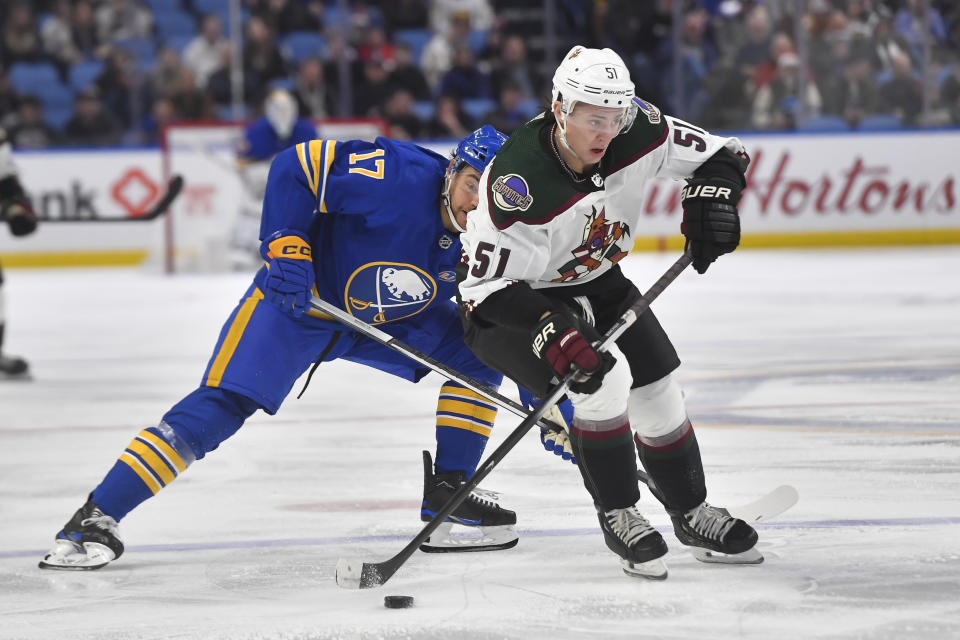 Arizona Coyotes defenseman Troy Stecher, right, shields the puck from Buffalo Sabres center Tyson Jost during the second period of an NHL hockey game in Buffalo, N.Y., Monday, Dec. 11, 2023. (AP Photo/Adrian Kraus)
