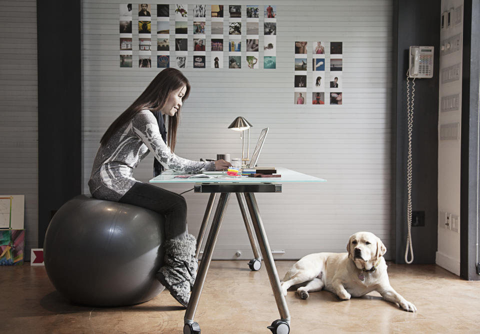 Japanese businesswoman sitting on exercise ball and working at desk