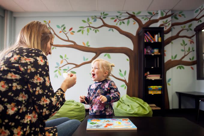 Woman showing piece of magnetic fishing game to girl at preschool