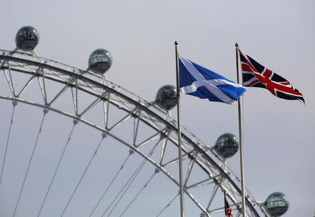 A Scottish Saltire flag and British Union flag fly together with the London Eye behind in London September 19, 2014. REUTERS/Luke MacGregor