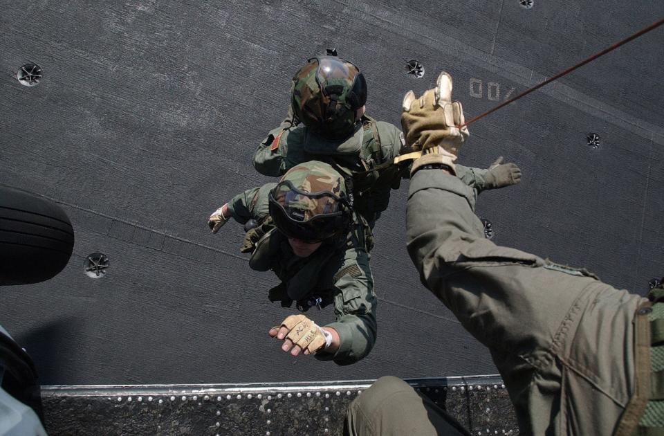 Aircrewmen are lifted from the flight deck of USS John F. Kennedy by helicopter