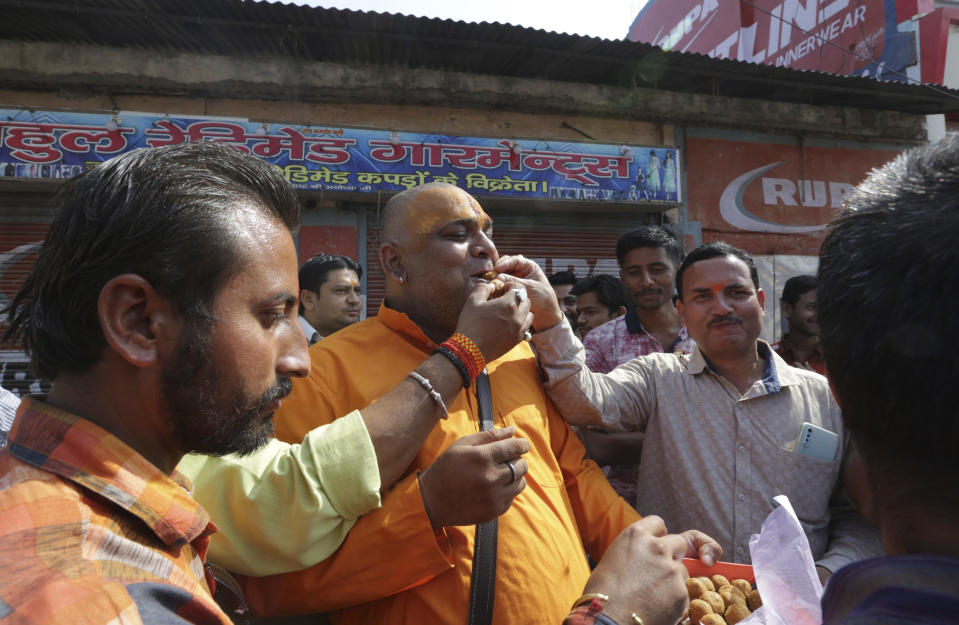 Hindus celebrate with sweets after a verdict in a decades-old land title dispute between Muslims and Hindus, in Ayodhya, India , Saturday, Nov. 9, 2019. India's Supreme Court on Saturday ruled in favor of a Hindu temple on a disputed religious ground and ordered that alternative land be given to Muslims to build a mosque. The dispute over land ownership has been one of the country's most contentious issues. (AP Photo/Rajesh Kumar Singh)