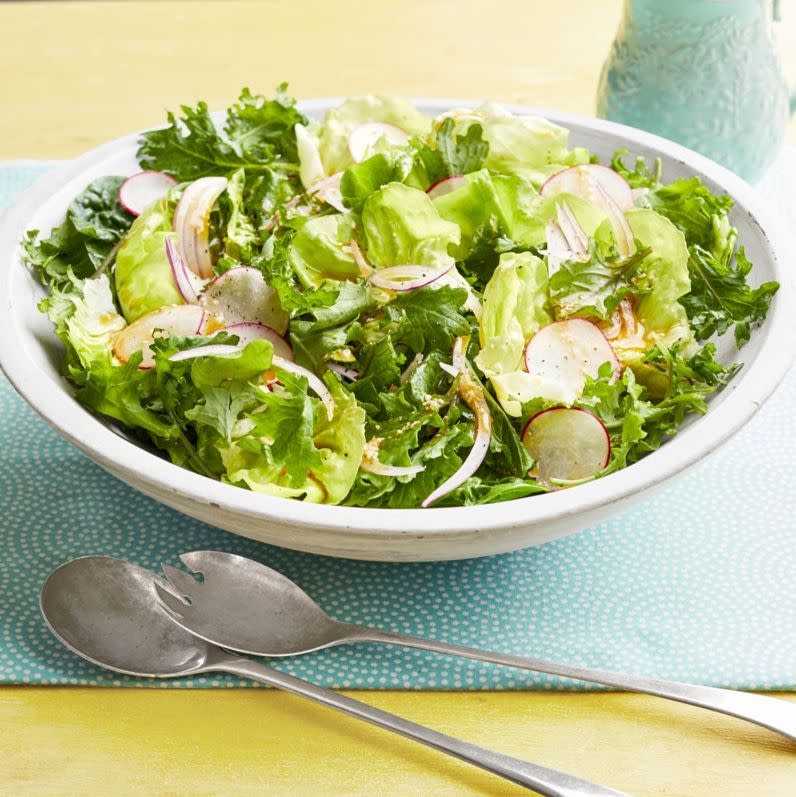 spring salad with radishes on light blue linen and serving spoons