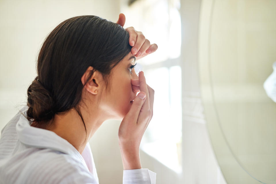 Woman putting in contact lenses. (Getty Images)