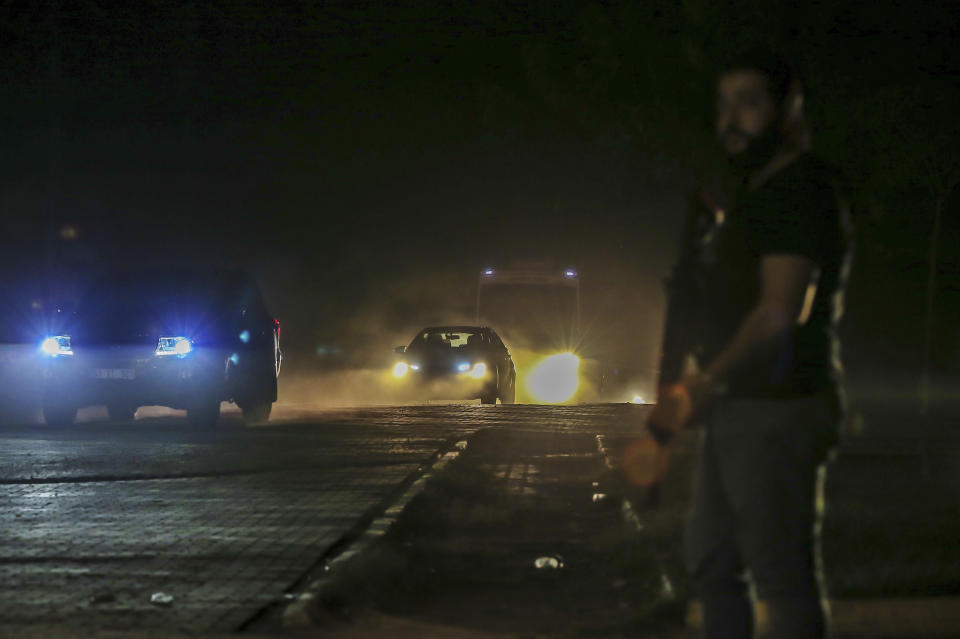 In this late Friday, Oct. 18, 2019 photo, Turkish police and army cars escort vans and buses returning from Syria, reportedly carrying IS group members and their families, at the border town of Akcakale, Sanliurfa province, southeastern Turkey. Turkey's interior minister Suleyman Soylu said Saturday, Oct. 19, that 41 Islamic State members were re-captured in Syria and private IHA news agency said the Turkish nationals among the re-captured were brought over to Turkey in vans. Turkey's President Recep Tayyip Erdogan Erdogan said the Turks captured would be imprisoned and tried in Turkey. (AP Photo/Emrah Gurel)