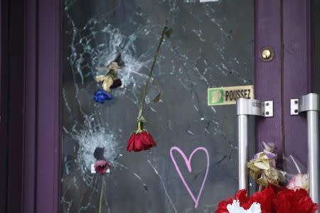 Flowers are seen in the holes from bullet impacts on the door of the"Casa Nostra" pizzeria in Paris, France, December 4, 2015, three weeks after shooting attacks which killed 130 people in the French capital. REUTERS/Charles Platiau