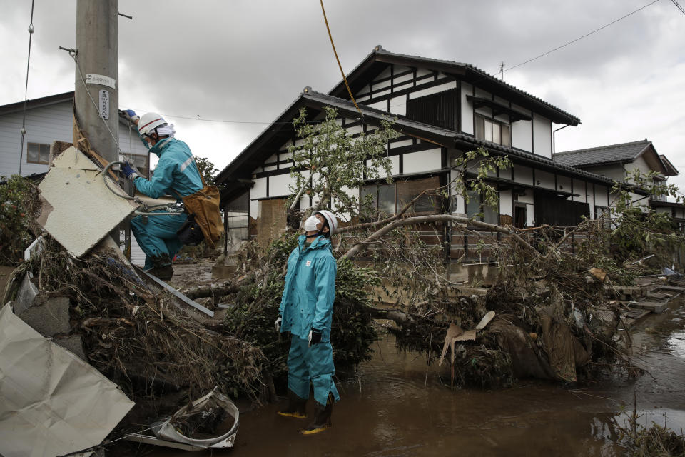 Electricity workers work in a neighborhood devastated by Typhoon Hagibis Tuesday, Oct. 15, 2019, in Nagano, Japan. More victims and more damage have been found in typhoon-hit areas of central and northern Japan, where rescue crews are searching for people still missing. (AP Photo/Jae C. Hong)