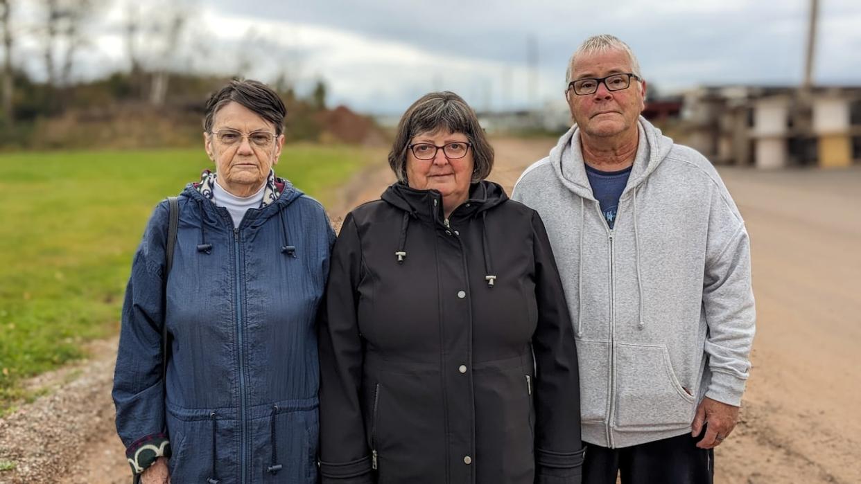 Anna Hardy, left, Dale MacInnis, and Pierre Gallant — residents who live near a gravel pit in Charlottetown and say they're fed up with debris flying off dump trucks. ( Shane Hennessey/CBC - image credit)