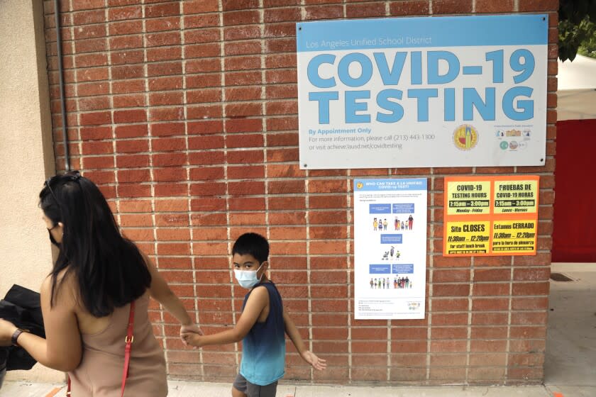 NORTHRIDGE, CA - AUGUST 11, 2021 - - Skyzell Touch, 6, is pulled along by his mother Raizah Touch as the first grader goes to be tested for COVID-19 before he begins to attend classes on Monday at Northridge Middle School in Northridge on August 11, 2021. Some parents also received the test for COVID. LAUSD has the most robust COVID-19 testing protocol in California, is requiring all students and teachers to be tested weekly. California could be the first state in the U.S. with a teacher vaccine mandate. Gov. Newsom announced today that all teachers and school staff in the state will be required to get vaccinated or submit to weekly testing. (Genaro Molina / Los Angeles Times)